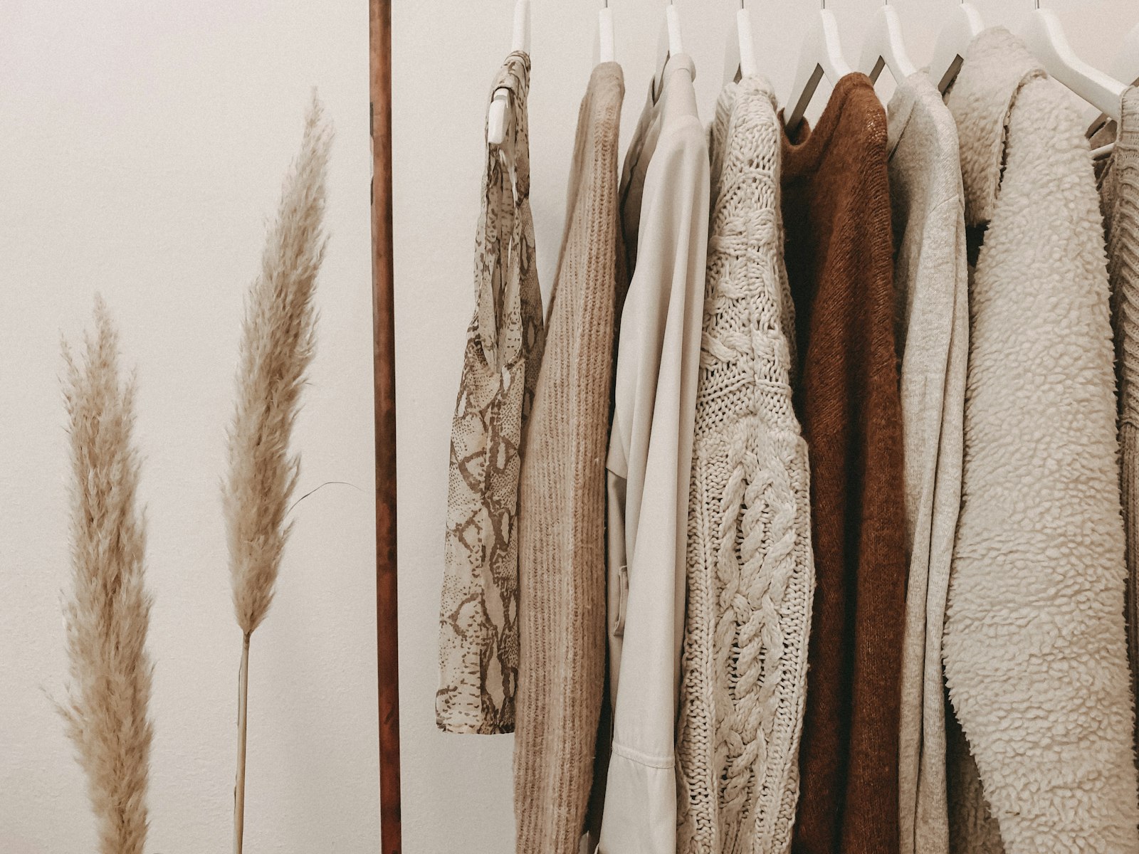 Ivory and camel knits hanging in a row